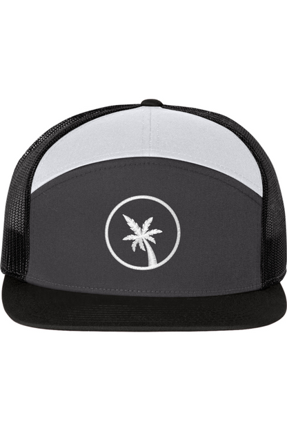 A seven -panel trucker hat with a solid black front panel and brim. The top panel is white. The back two panels are black mesh. The front of the hat features a seven frond palm tree in white thread. The hat has a slightly curved brim and a visible button on the top.