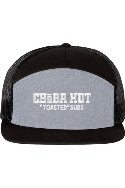 A seven -panel trucker hat with a solid grey front panel between a black top panel and brim. The back two panels are black mesh. The front of the hat features the white stylized text 'CHEBA HUT "TOASTED" SUBS'. The hat has a slightly curved brim and a visible button on the top.
