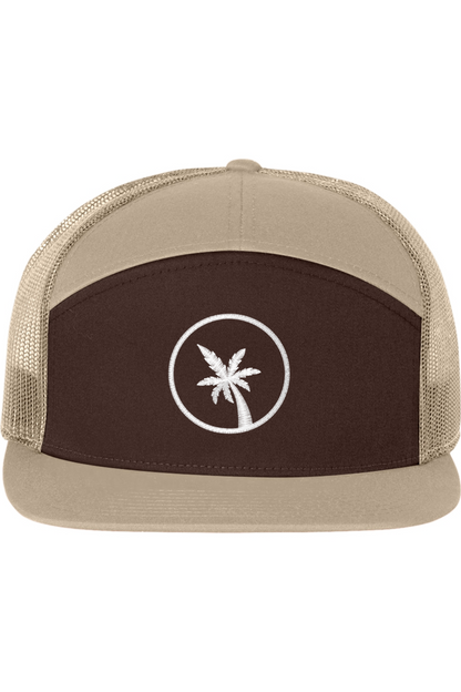 A seven -panel trucker hat with a solid brown front panel and brim. The back two panels are tan mesh. The front of the hat features a seven frond palm tree in white thread. The hat has a slightly curved brim and a visible button on the top.