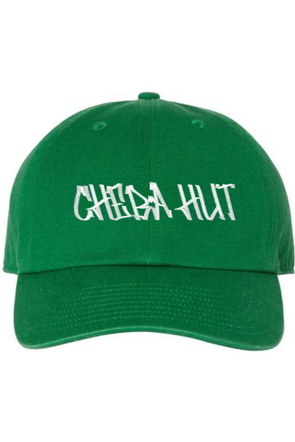 A kelly green baseball cap with a curved brim. The front of the cap features the white stylized text 'CHEBA HUT' embroidered across the center. The cap has a visible button on the top and an adjustable strap in the back (not visible).