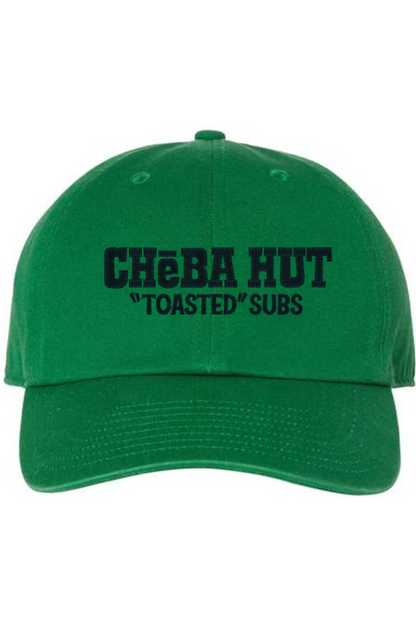 A Kelly green baseball cap with a curved brim. The front of the cap features the black stylized text 'CHEBA HUT "TOASTED" SUBS' embroidered across the center. The cap has a visible button on the top and an adjustable strap in the back (not visible).
