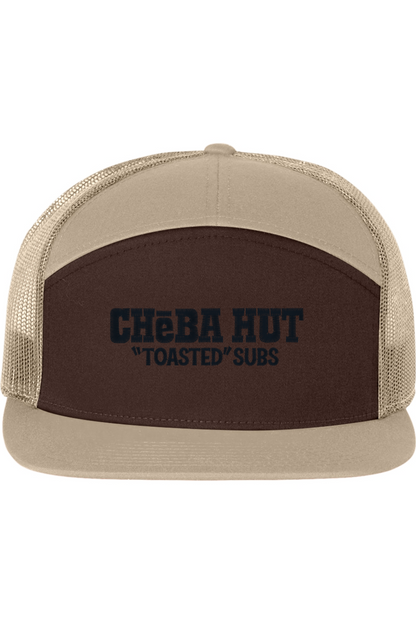 A seven-panel trucker hat with a solid brown  front panel and ten brim. The back two panels are tan mesh. The front of the hat features the black stylized text 'CHEBA HUT "TOASTED" SUBS'. The hat has a slightly curved brim and a visible button on the top.