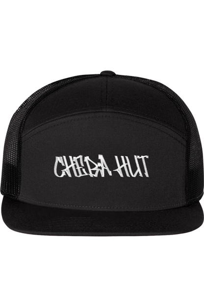 A seven-panel trucker hat with a solid black front panel and brim. The back two panels are black mesh. The front of the hat features the white stylized text 'CHEBA HUT'. The hat has a slightly curved brim and a visible button on the top.