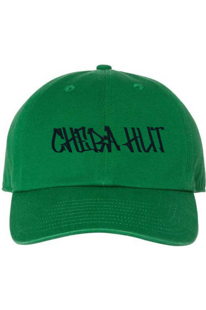 A Kelly green baseball cap with a curved brim. The front of the cap features the black stylized text 'CHEBA HUT' embroidered across the center. The cap has a visible button on the top and an adjustable strap in the back (not visible).