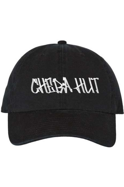 A black baseball cap with a curved brim. The front of the cap features the white stylized text 'CHEBA HUT' embroidered across the center. The cap has a visible button on the top and an adjustable strap in the back (not visible).