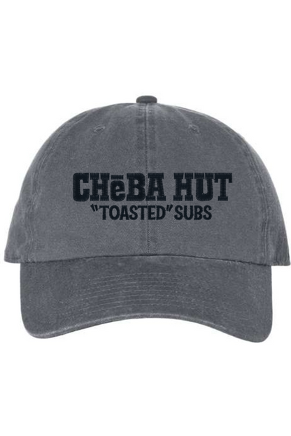 A charcoal baseball cap with a curved brim. The front of the cap features the black stylized text 'CHEBA HUT "TOASTED" SUBS' embroidered across the center. The cap has a visible button on the top and an adjustable strap in the back (not visible).