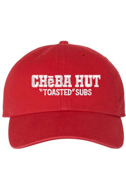 A red baseball cap with a curved brim. The front of the cap features the white stylized text 'CHEBA HUT "TOASTED" SUBS' embroidered across the center. The cap has a visible button on the top and an adjustable strap in the back (not visible).